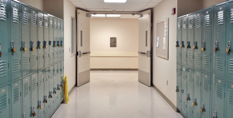 An empty hallway with green lockers on either side.