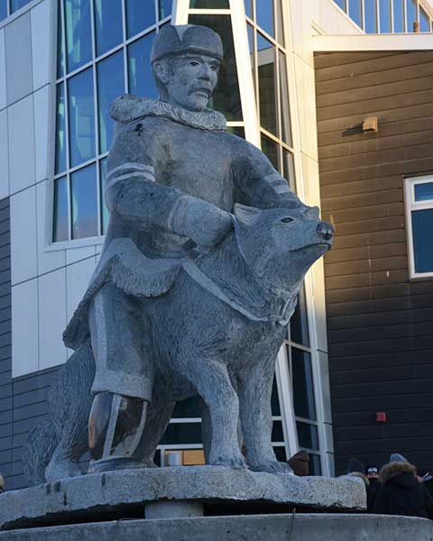 sculpture d'un gendarme spécial inuit harnachant son qimmiit, un chien de traîneau inuit