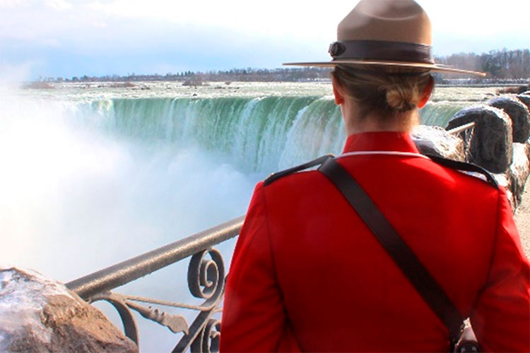 A Mountie in red serge stands in front of Horseshoe Falls