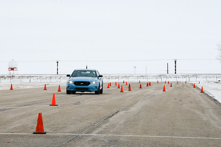 A car on a paved track with orange pylons.