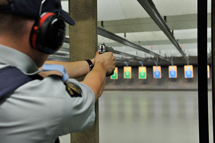 Un cadet braque un pistolet sur une cible en papier