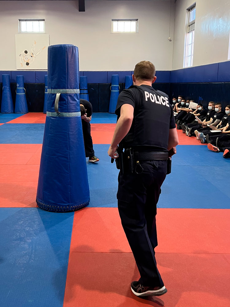 A cadet comes up to an obstacle in training. Others can be seen watching.