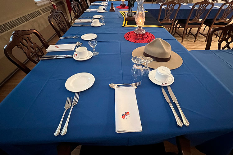 An empty table setting with a Stetson and over-turned drinking glasses.