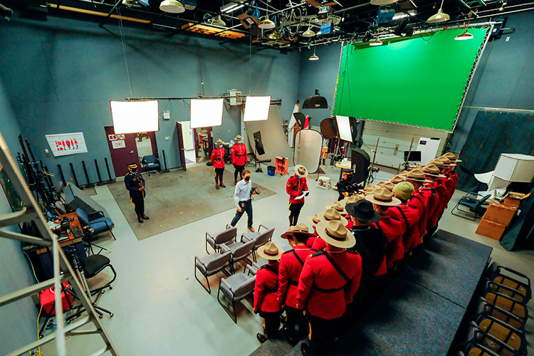 Behind the scenes of a photographer setting up a graduation photo of cadets in red serge.