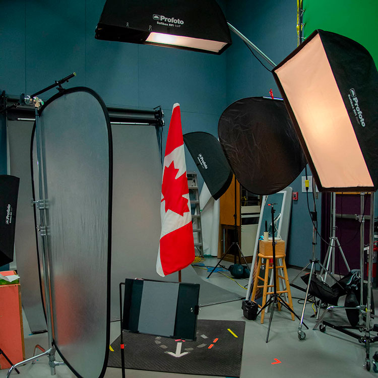 Des lampes, des réflecteurs et le drapeau canadien dans les coulisses du studio de photographie.