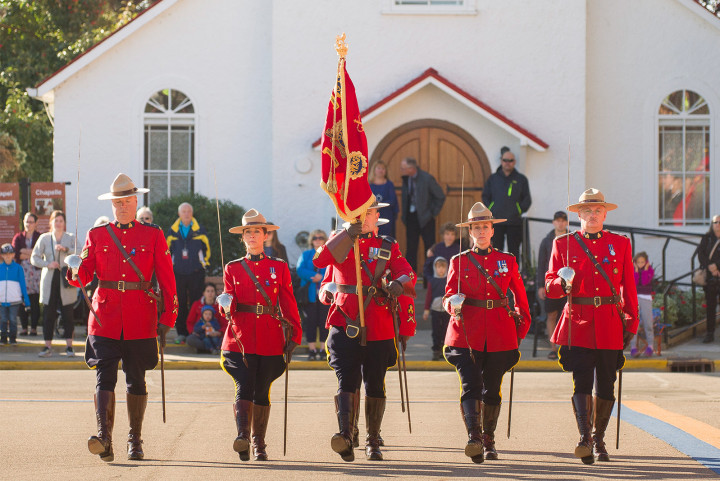 RCMP members with swords drawn march the RCMP Guidon onto the Parade Square.