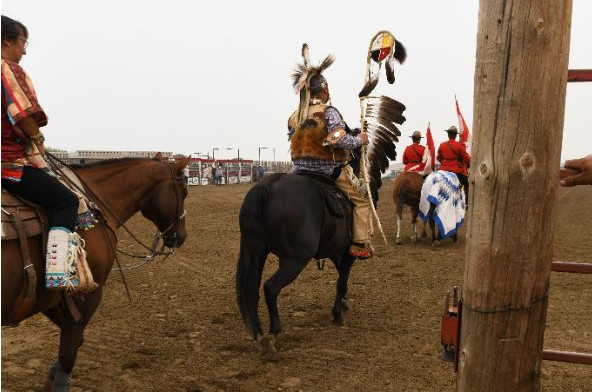 The group rides into the arena, followed by the other horse-riding flag-bearers