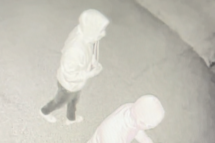 Two individuals spray-painting the exterior of the RCMP building