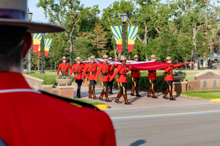 Une garde du drapeau en serge rouge porte le drapeau du Canada.