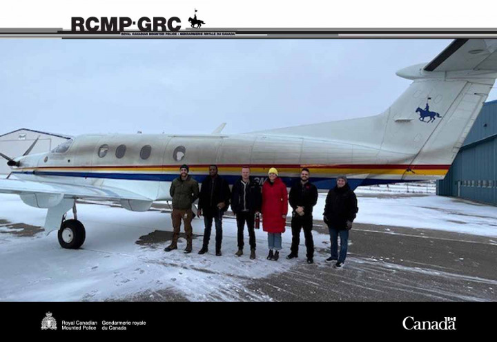 Six individuals standing in front of a plane. 