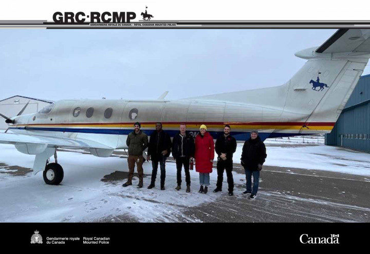 Six personnes devant un avion. 