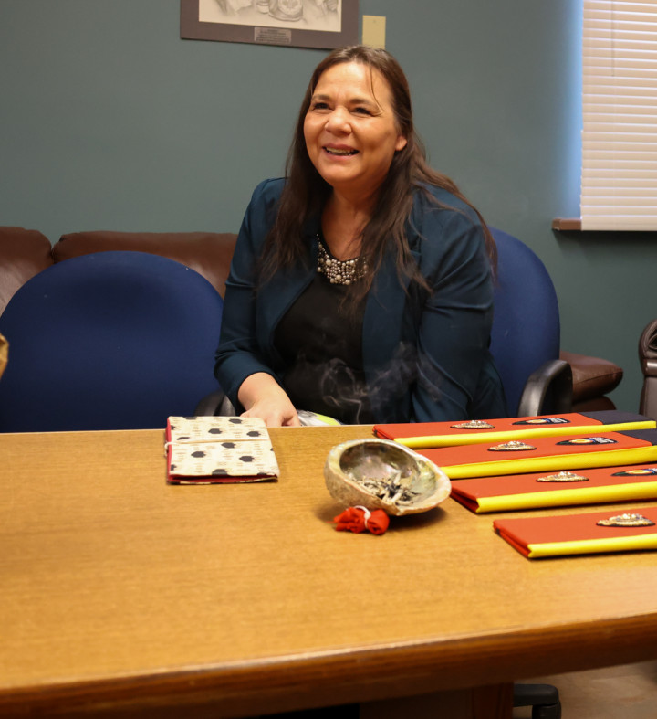 Tiffany Sark seated with smudging bowl and eagle feathers at a table