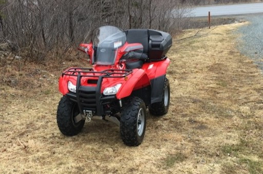 Un VTT Honda rouge stationné sur le gazon.