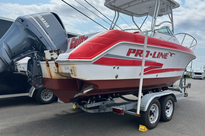 Un moteur hors-bord Yamaha, de l'année 2023, attaché à un bateau Pro Line rouge et blanc, de 2002, qui se trouve sur une remorque à bateau Venture, de 2015.