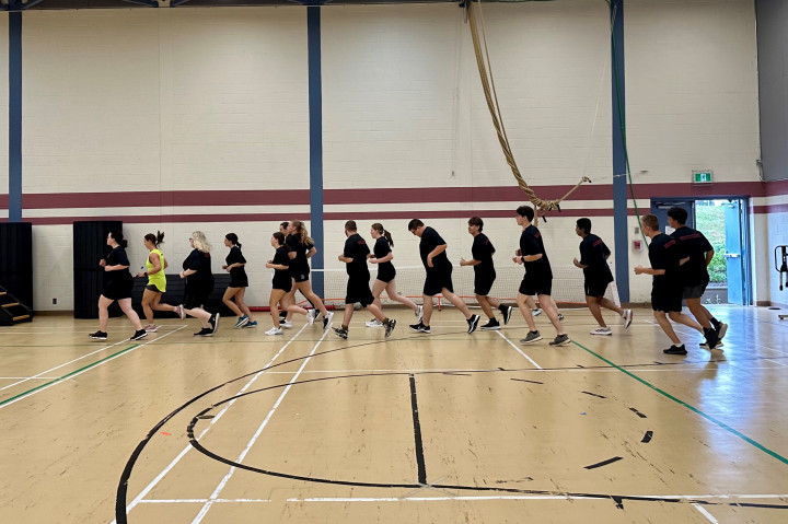 A group of students are running inside a gymnasium. 